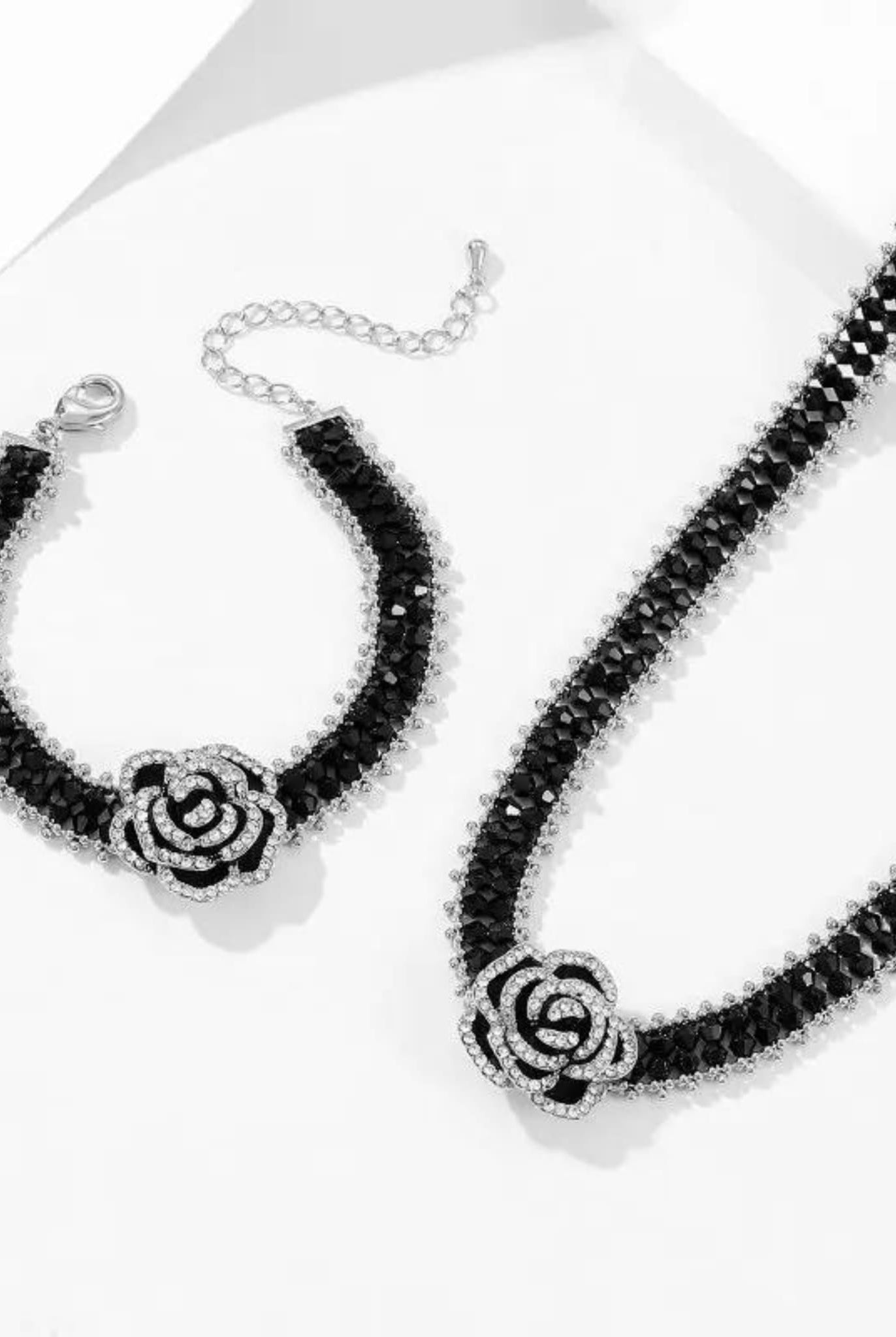 Adjustable black beaded bracelet with a crystal-studded camellia flower.