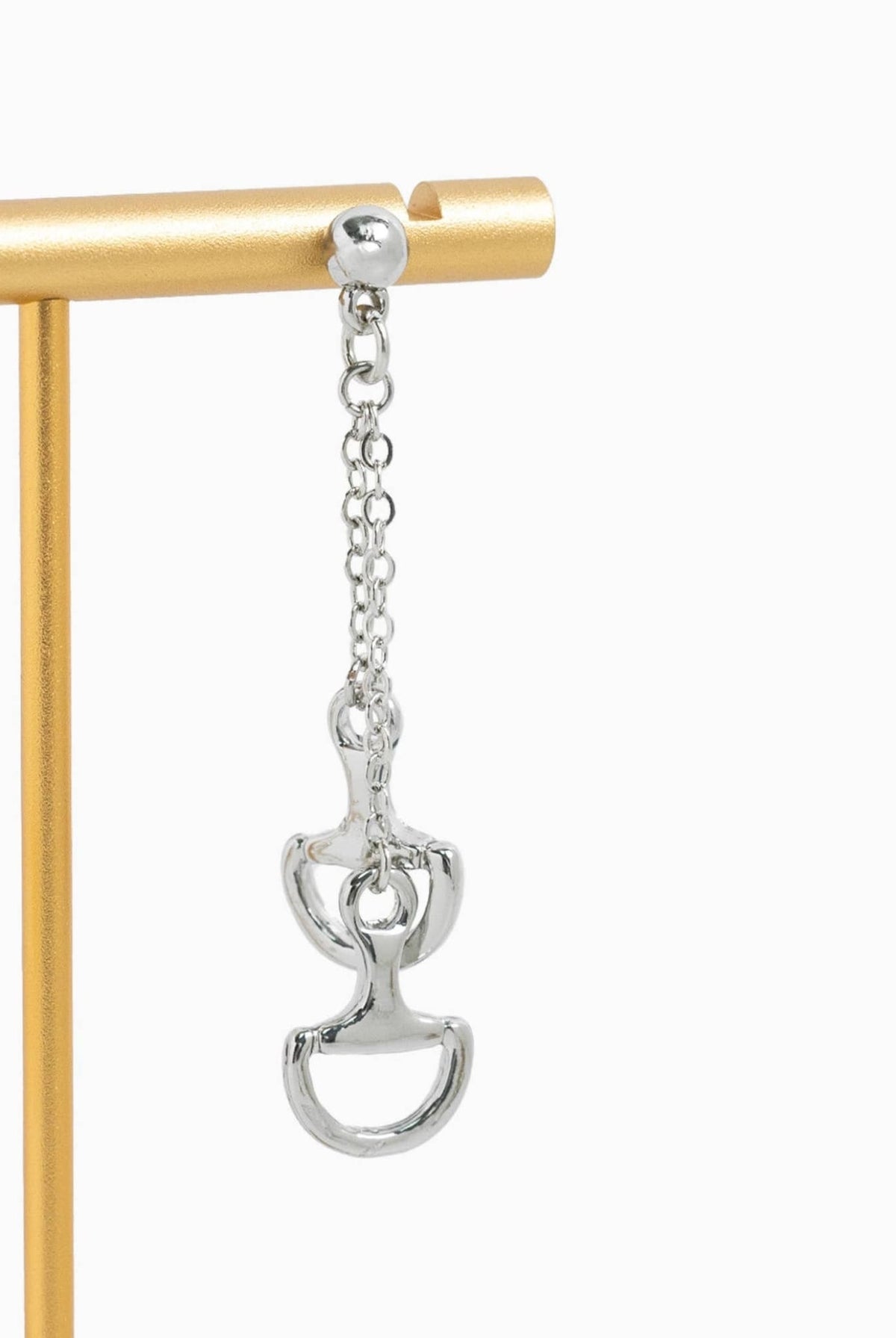 Silver horse bit dangle earring displayed on a jewelry stand.