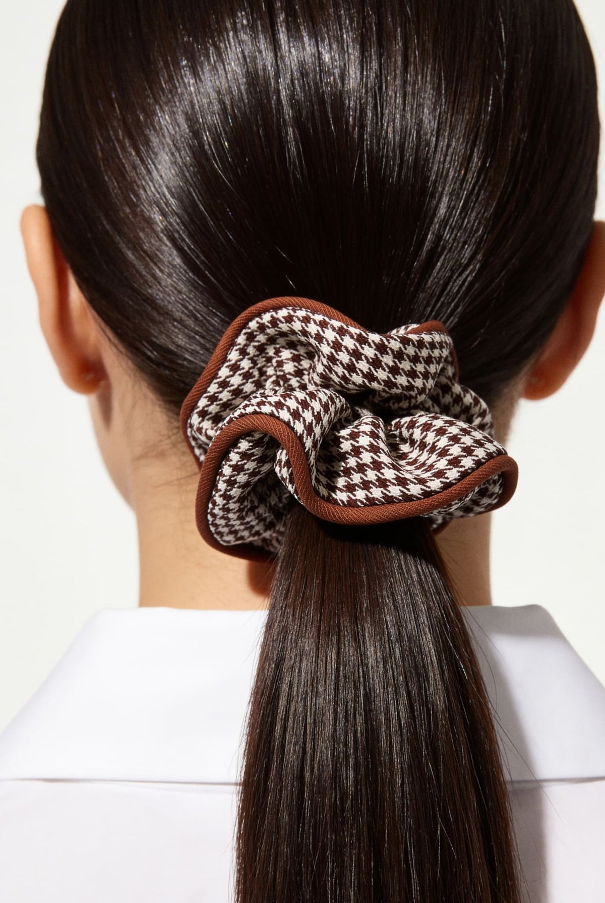 Houndstooth hair scrunchie in brown styled in a sleek ponytail.