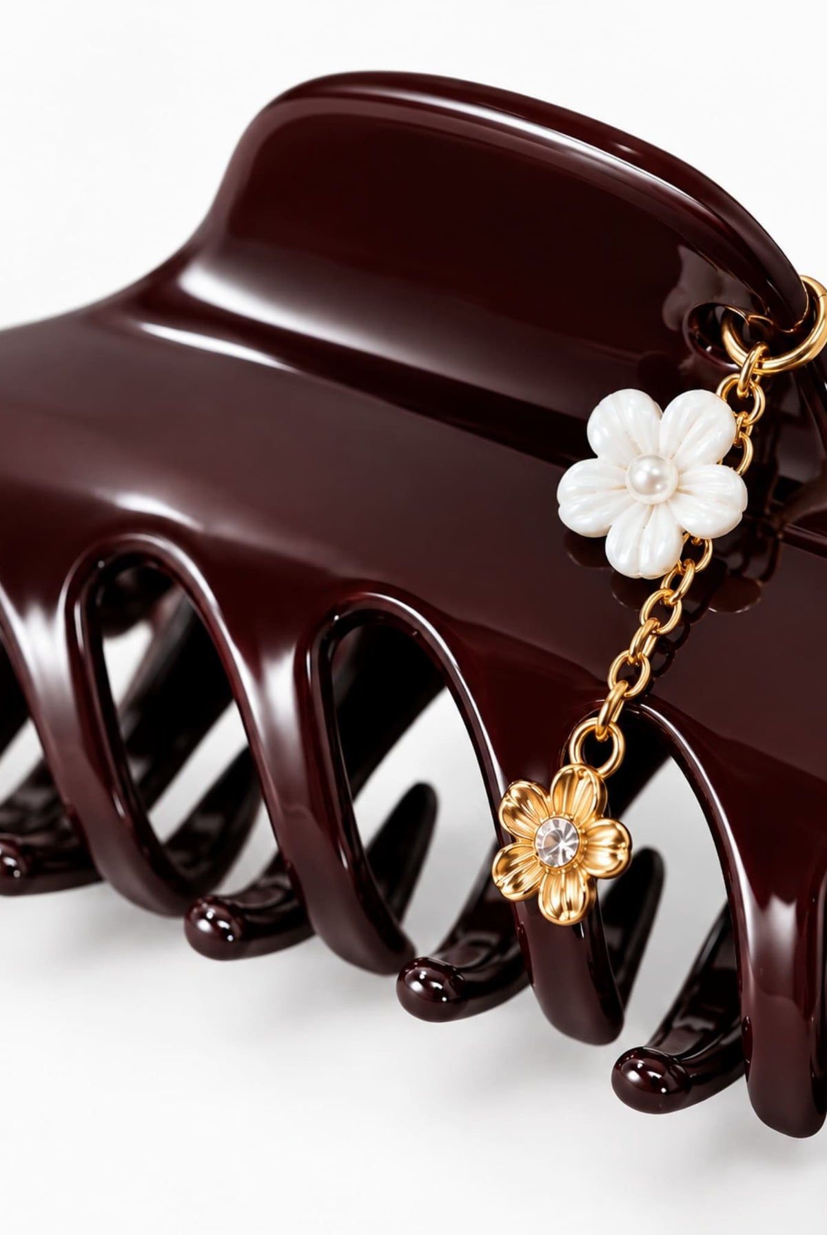 Close-up of burgundy hair claw with gold-tone chain and floral charms.