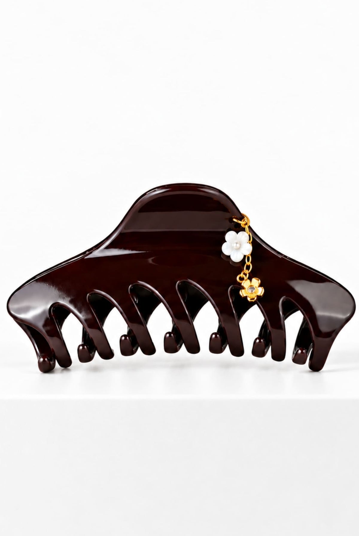 Large burgundy hair claw with delicate floral charm detail.