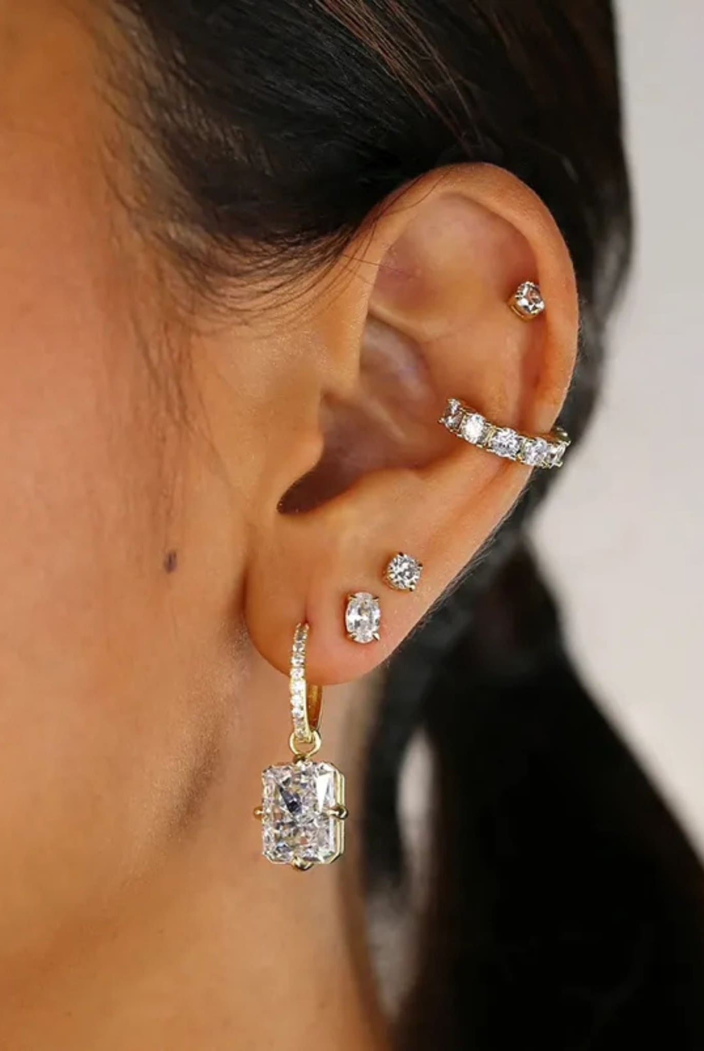 Gold radiant cut earrings worn, featuring elegant sparkle and drop design.