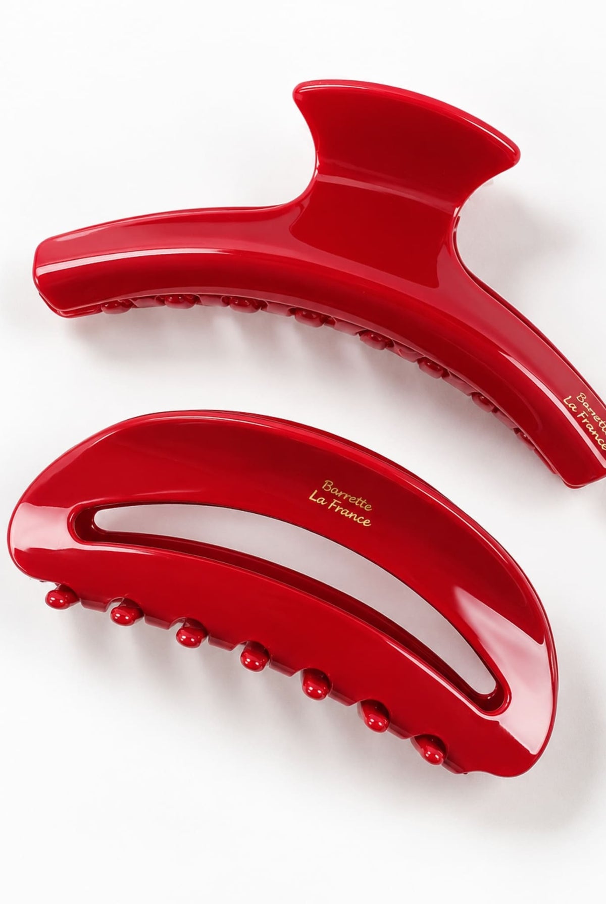 Two scarlet red hair claw clips with curved shapes, open cutout details and rounded teeth, viewed from above.