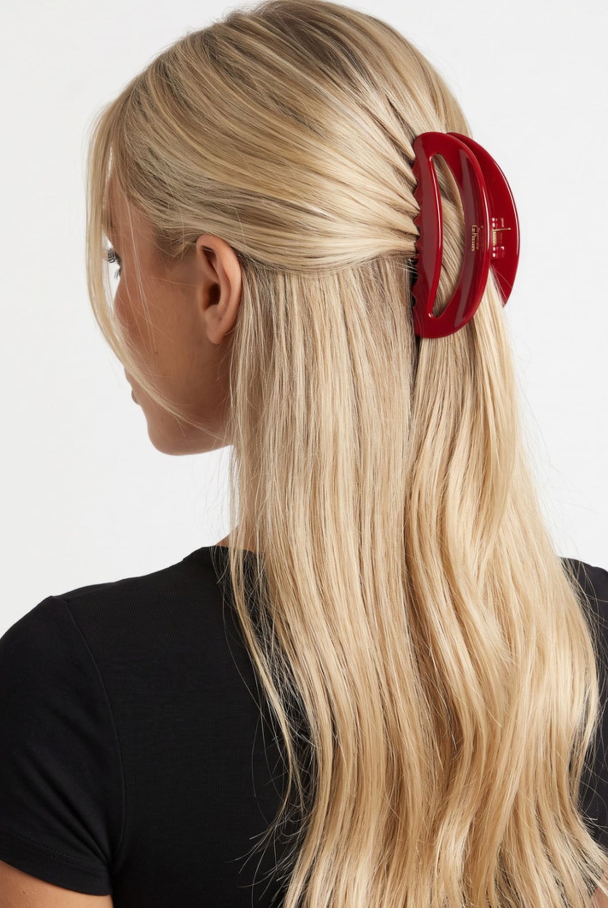 Large red hair claw clip securing blonde hair in a half-up hairstyle, shown from the side.