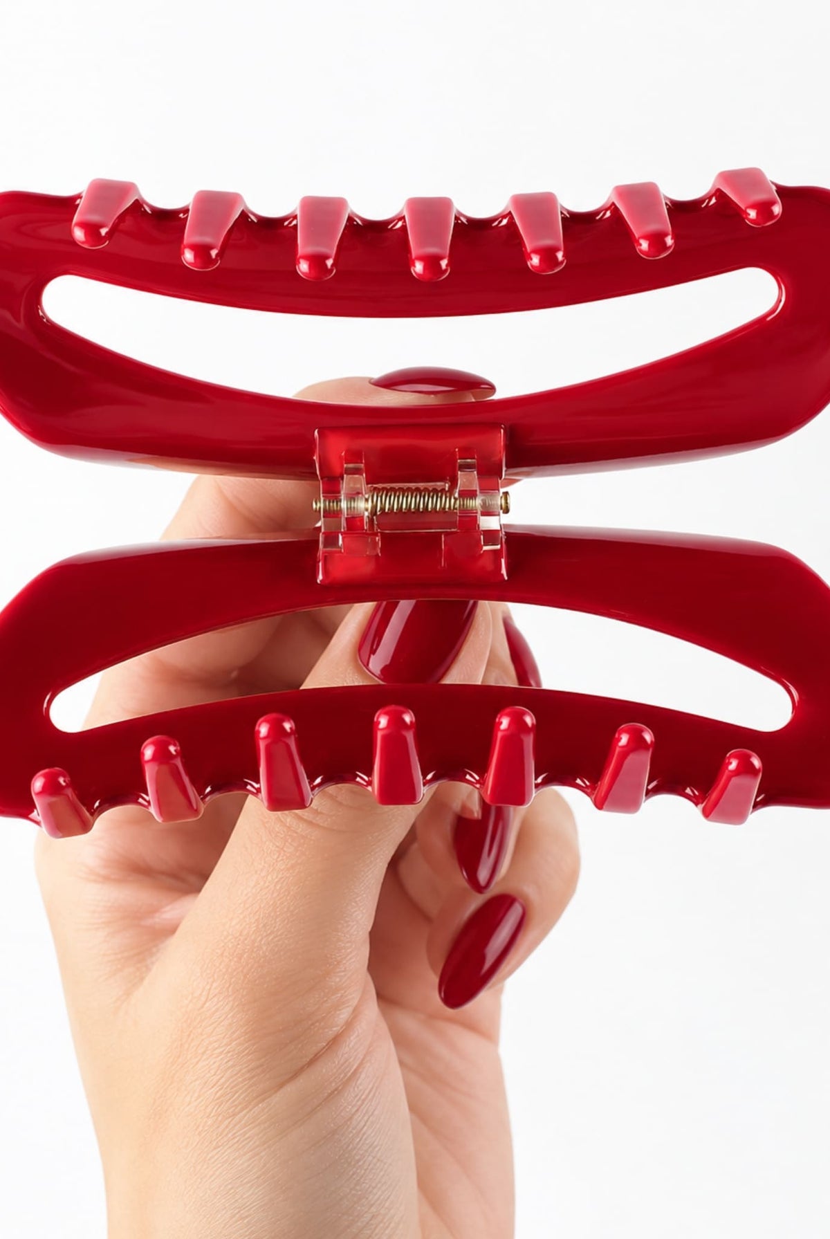 Close-up of the red hair claw clip opened to reveal its interlocking teeth and gold-tone spring mechanism.