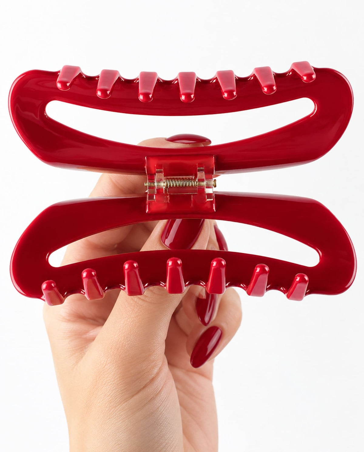 Close-up of the red hair claw clip opened to reveal its interlocking teeth and gold-tone spring mechanism.