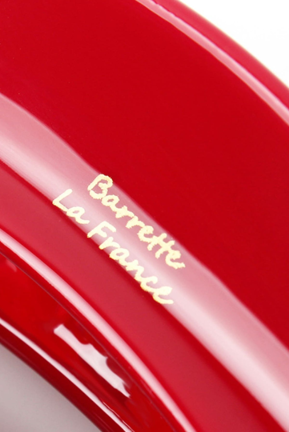 Macro detail of the glossy red hair claw clip featuring gold Barrette La France lettering.