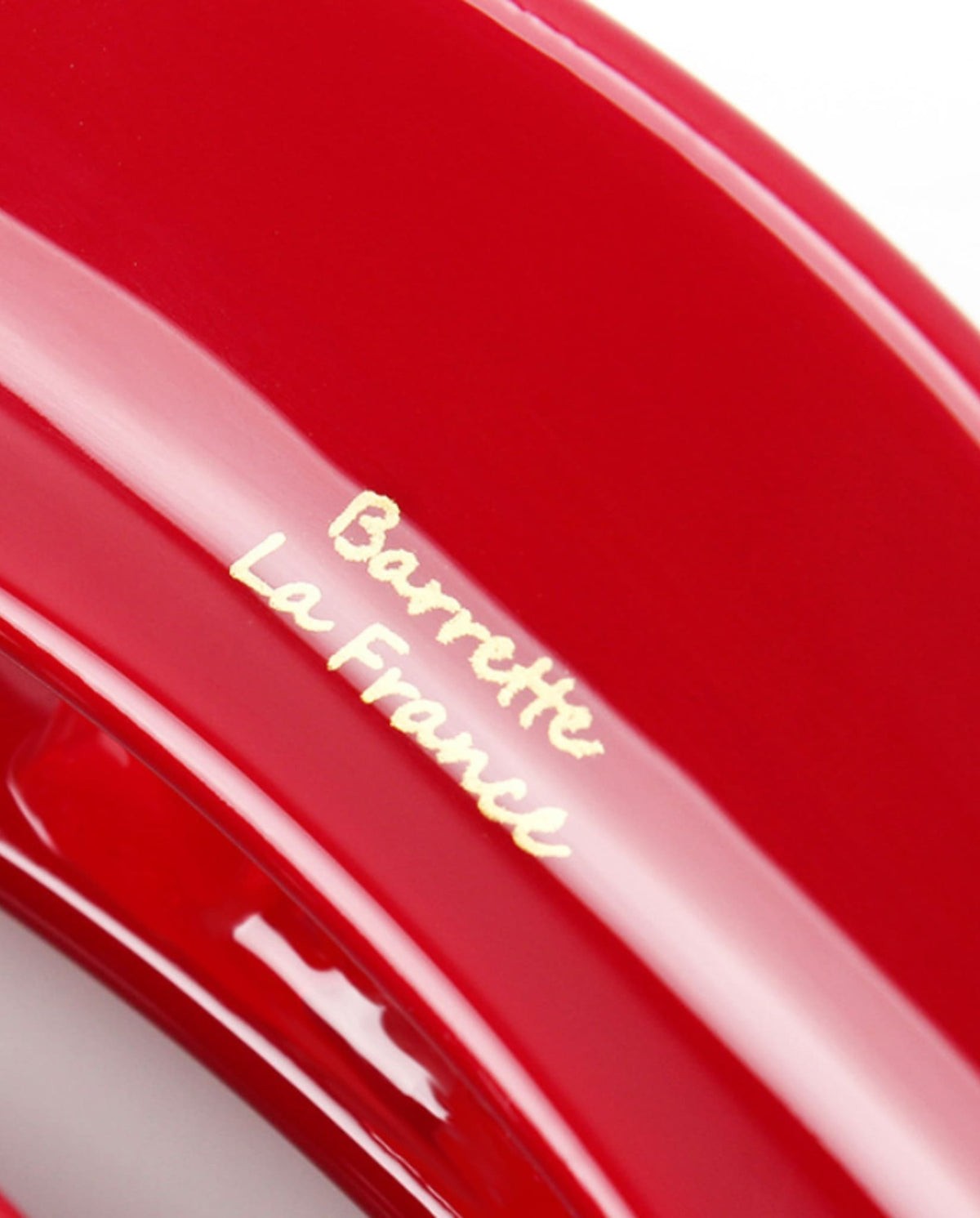 Macro detail of the glossy red hair claw clip featuring gold Barrette La France lettering.
