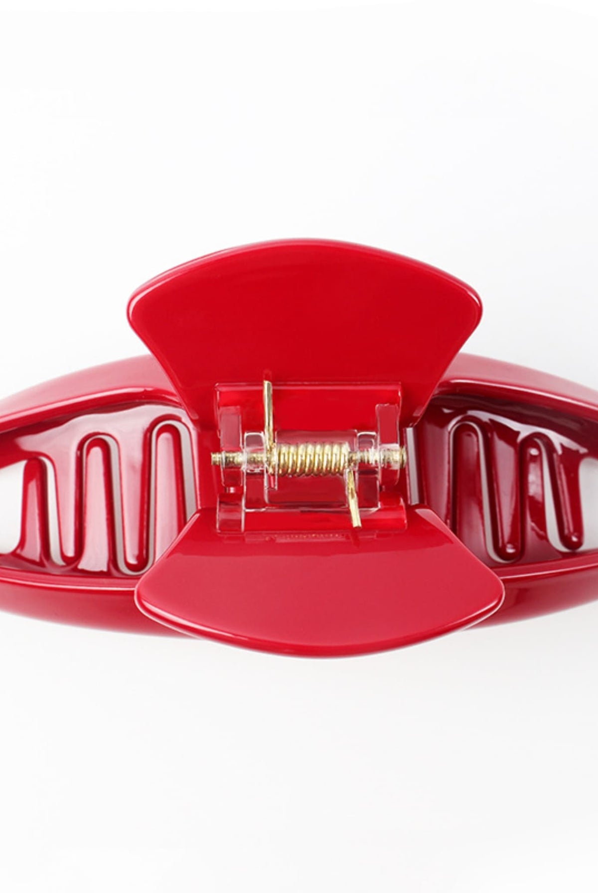 Close-up of an open red hair claw clip showing its curved teeth and metal spring mechanism.
