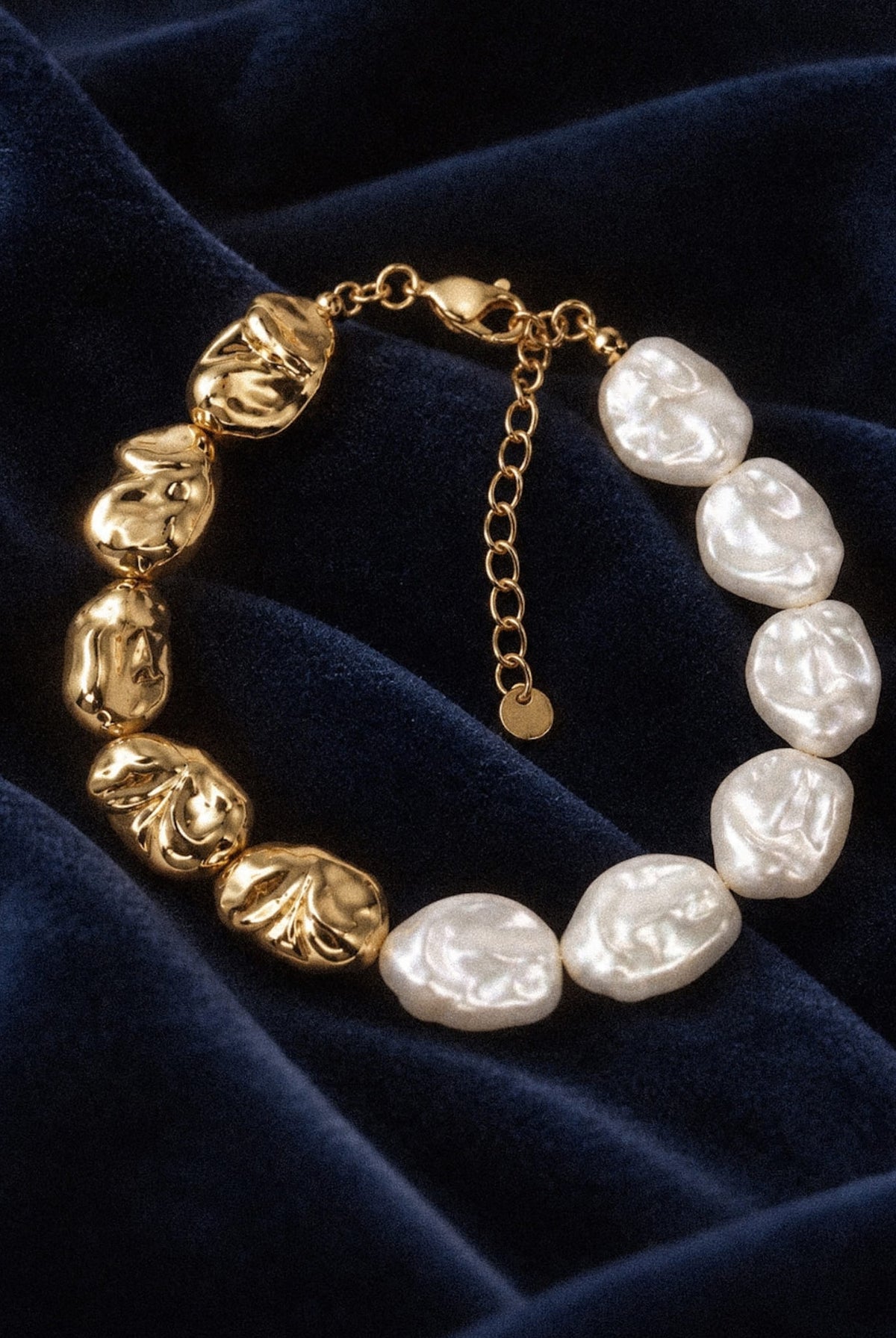 Sculpted Pearl Bracelet with irregular white pearl beads and textured gold-tone beads on navy velvet.