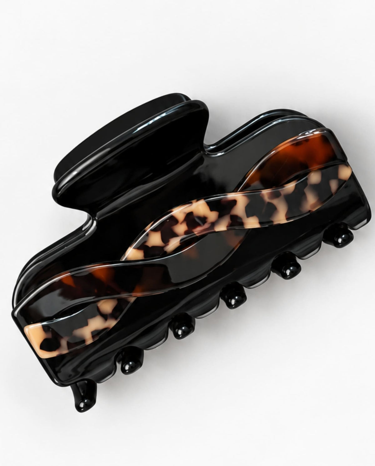 Glossy black hair claw clip with an intertwined tortoiseshell pattern in brown and beige, shown at an angle on a white background.