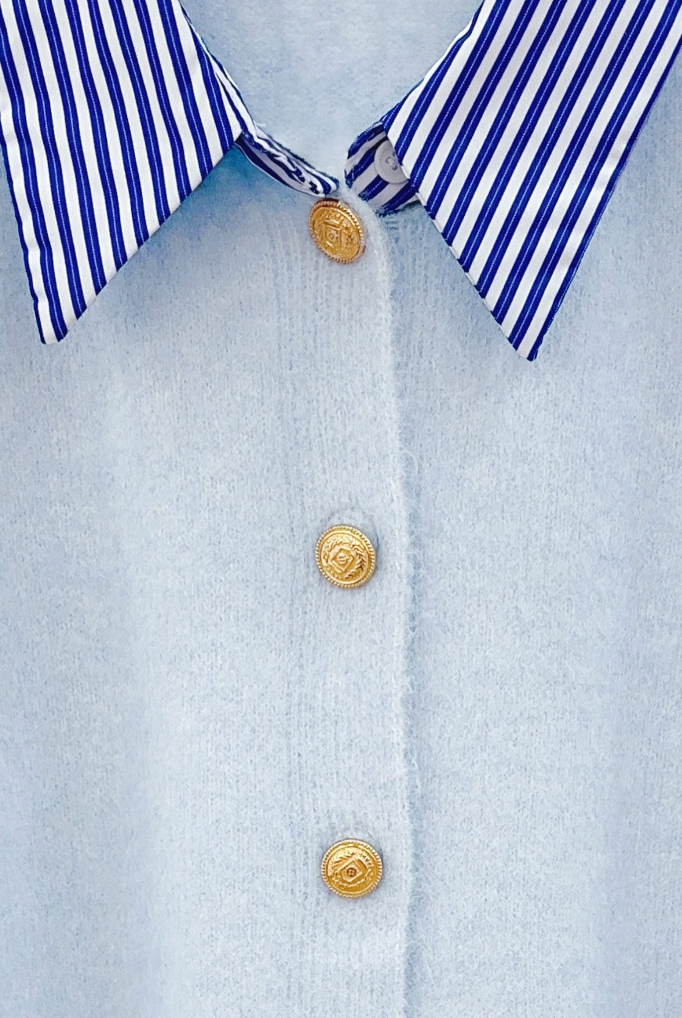 Detailed view of the striped collar and gold buttons on the blue cardigan.
