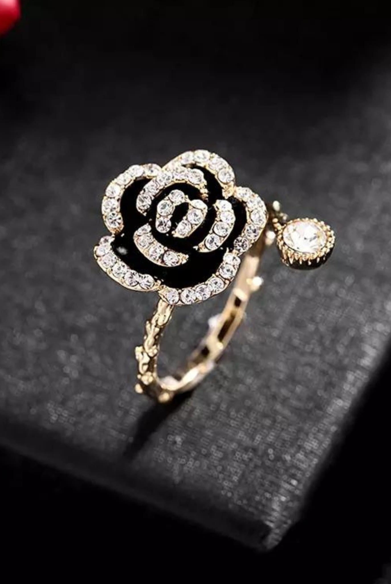Gold floral ring with a black Camellia design and sparkling rhinestones.