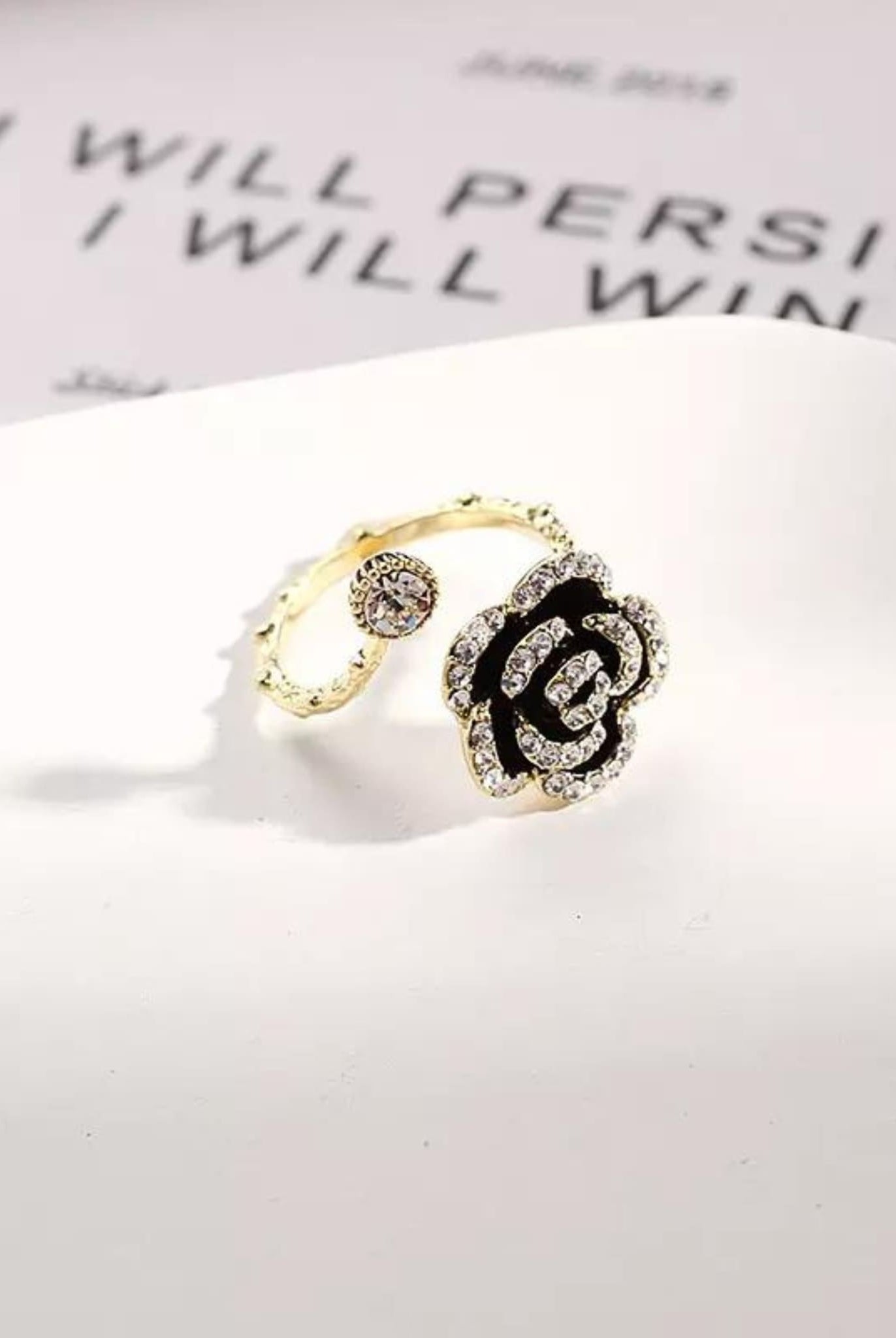Gold adjustable Camellia ring with black enamel and rhinestone accents.