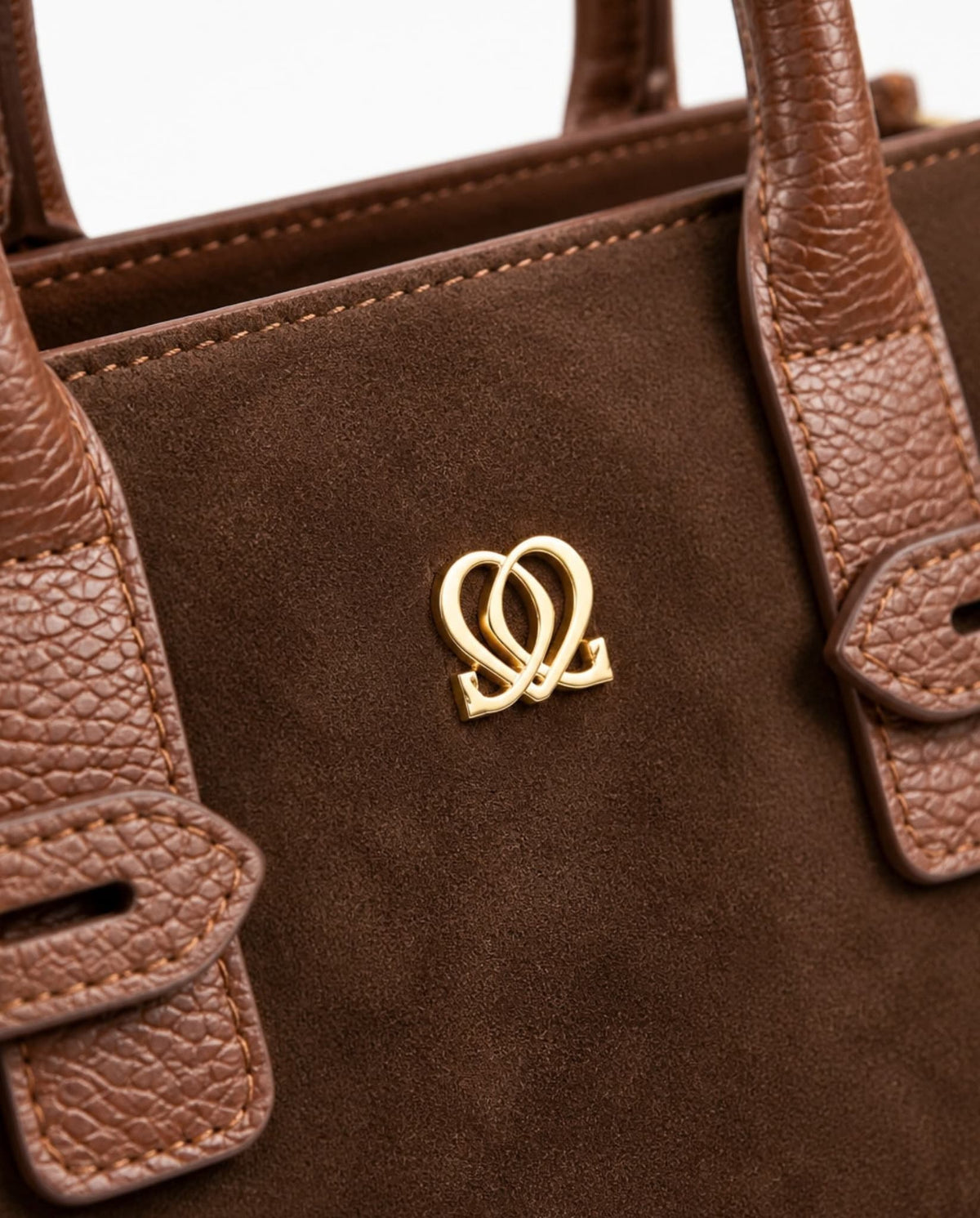 Close-up of Classic Leather Handbag In Brown showing brown suede-like material, textured handles, stitching and gold-tone emblem.