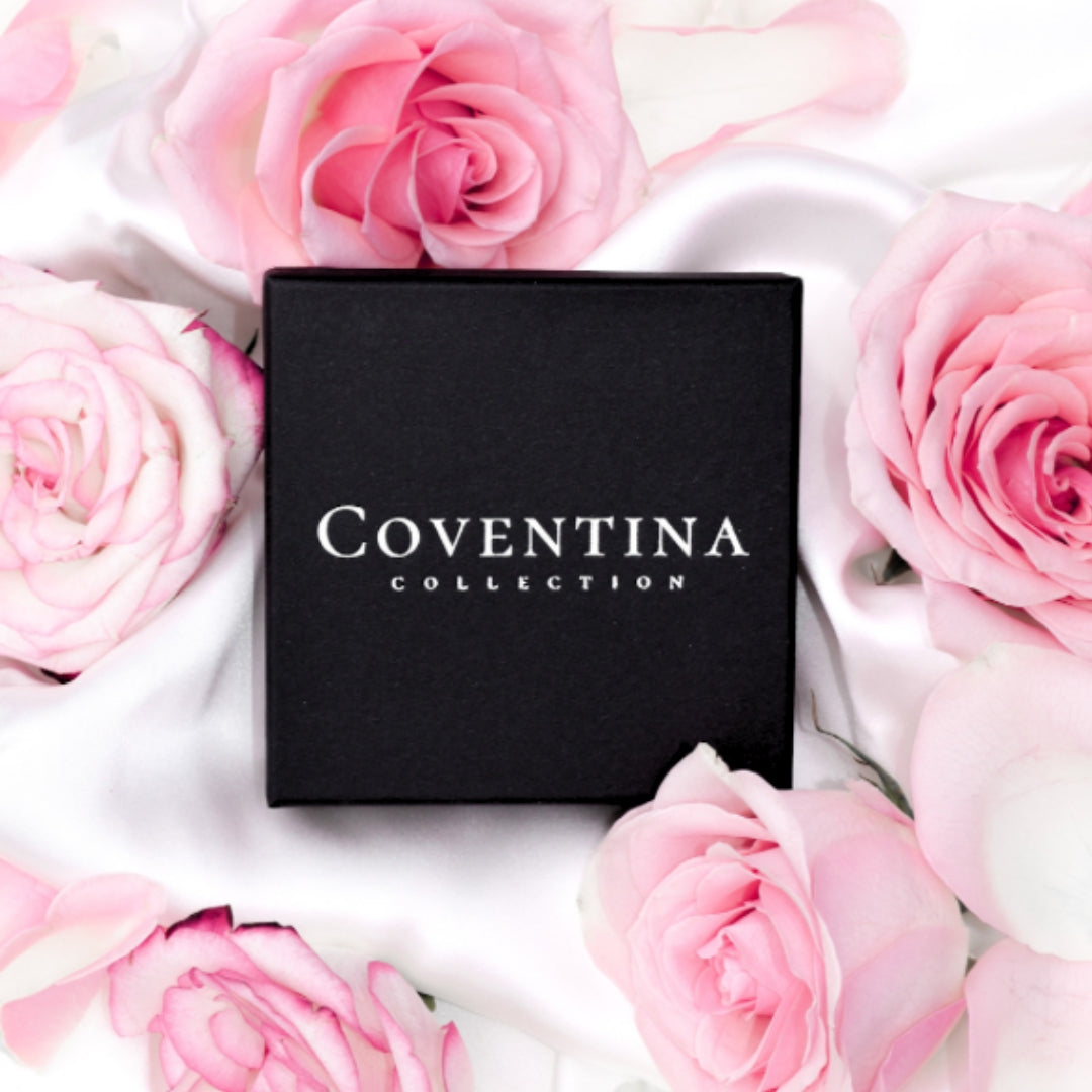 Coventina Collection branded box surrounded by pink roses, showcasing luxury.