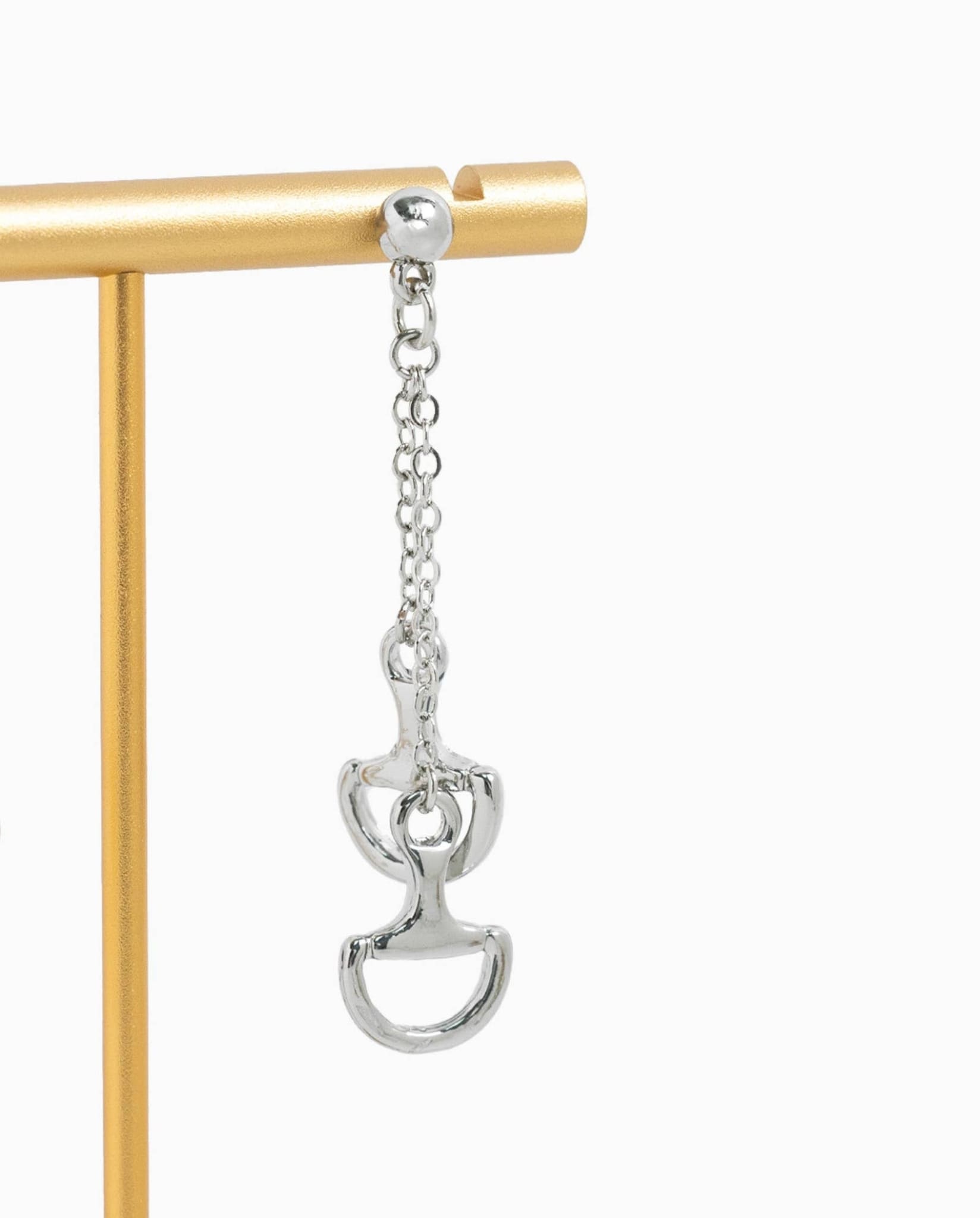 Silver horse bit dangle earring displayed on a jewelry stand.