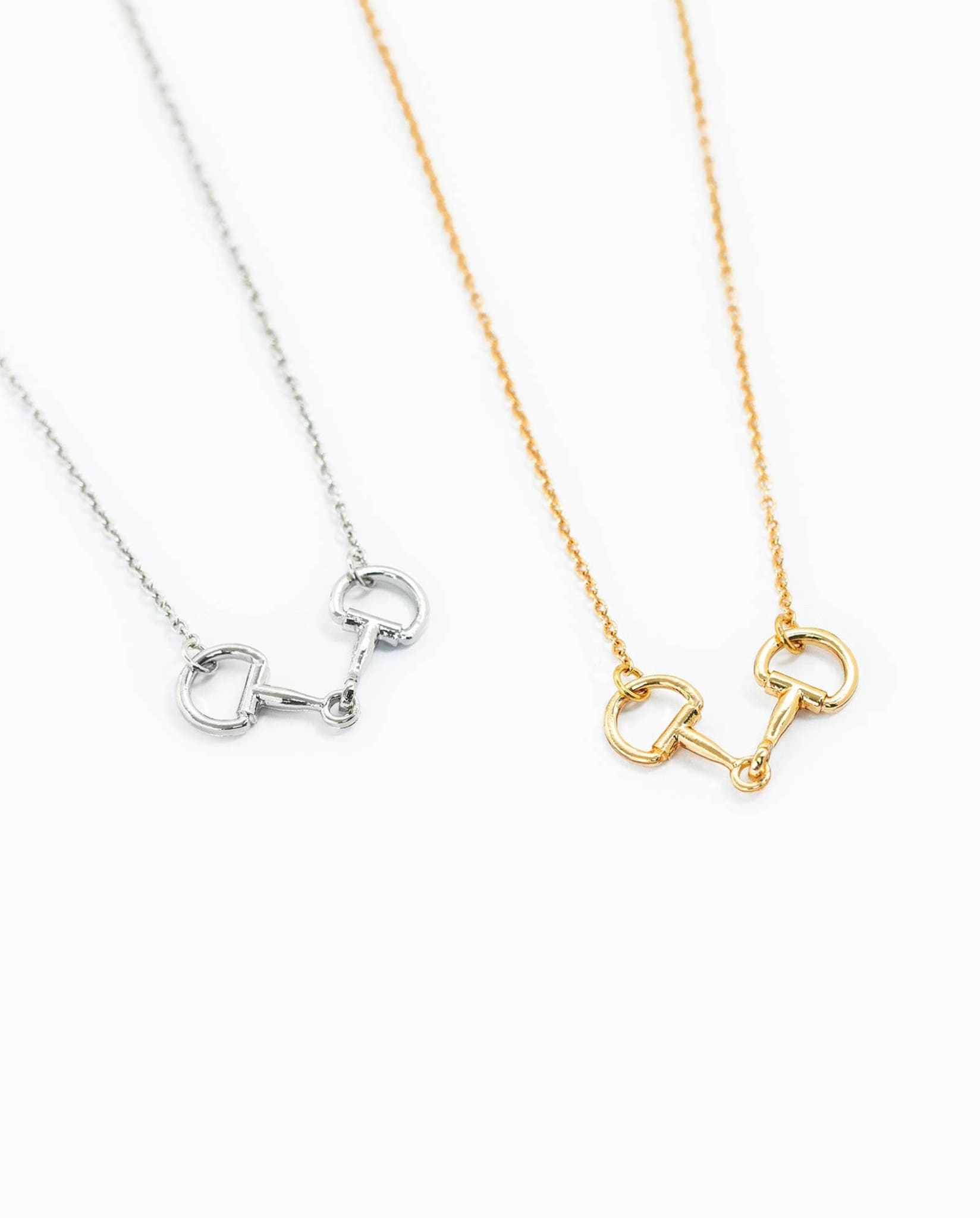 Gold and silver horse bit necklaces displayed together on white background.