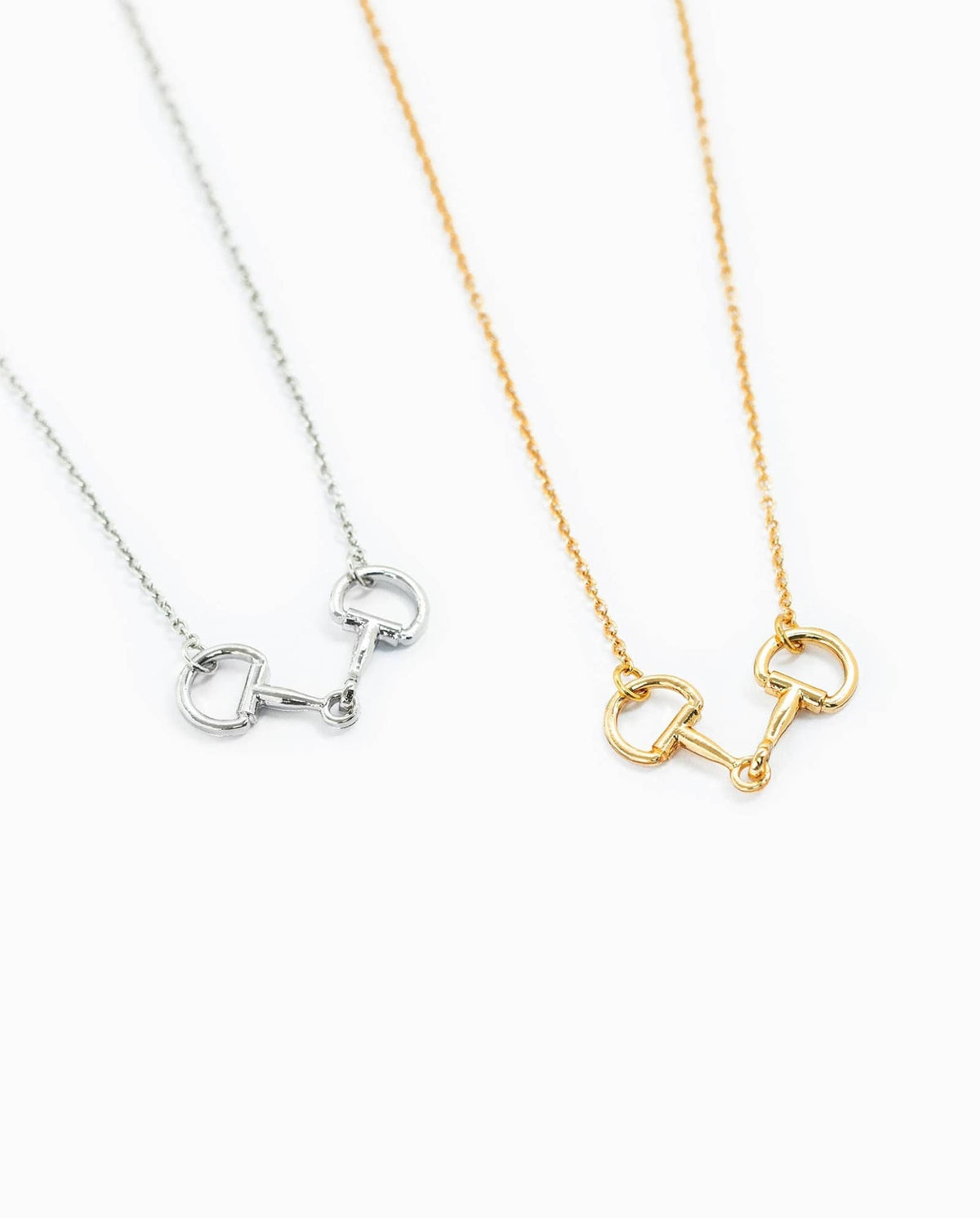 Gold and silver horse bit necklaces displayed together on white background.