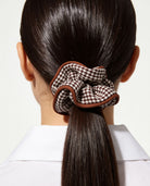 Houndstooth hair scrunchie in brown styled in a sleek ponytail.