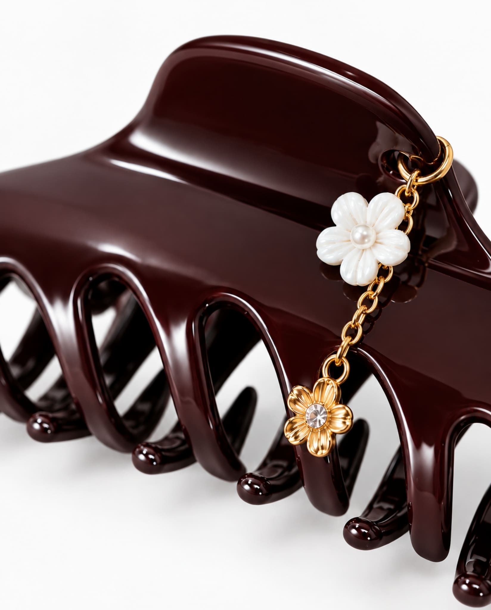 Close-up of burgundy hair claw with gold-tone chain and floral charms.