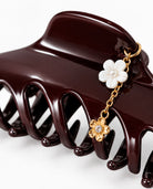 Close-up of burgundy hair claw with gold-tone chain and floral charms.