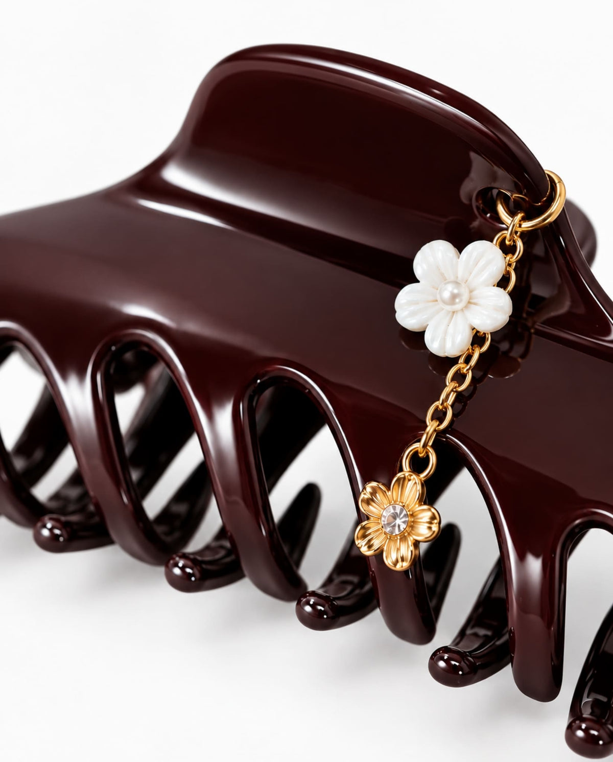 Close-up of burgundy hair claw with gold-tone chain and floral charms.