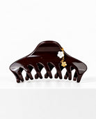 Large burgundy hair claw with delicate floral charm detail.