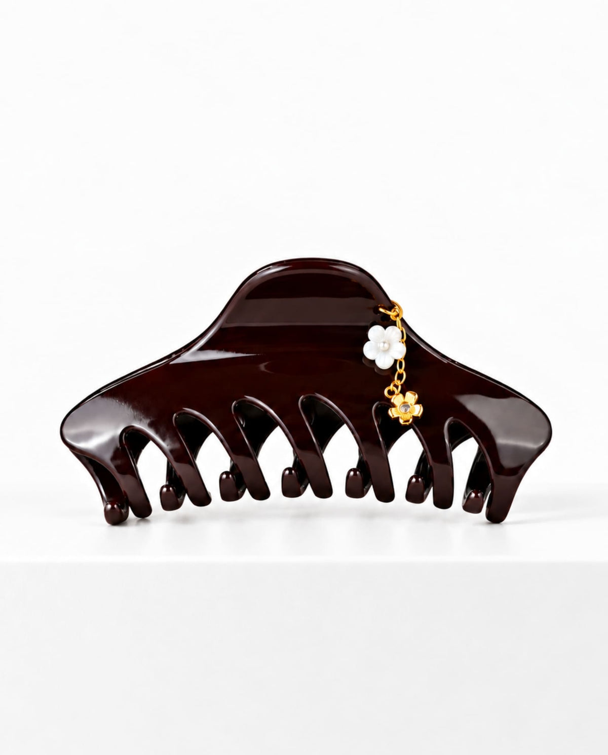 Large burgundy hair claw with delicate floral charm detail.