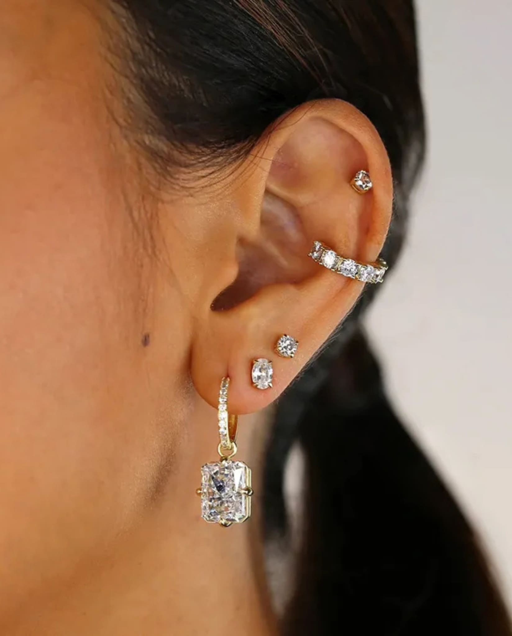 Gold radiant cut earrings worn, featuring elegant sparkle and drop design.