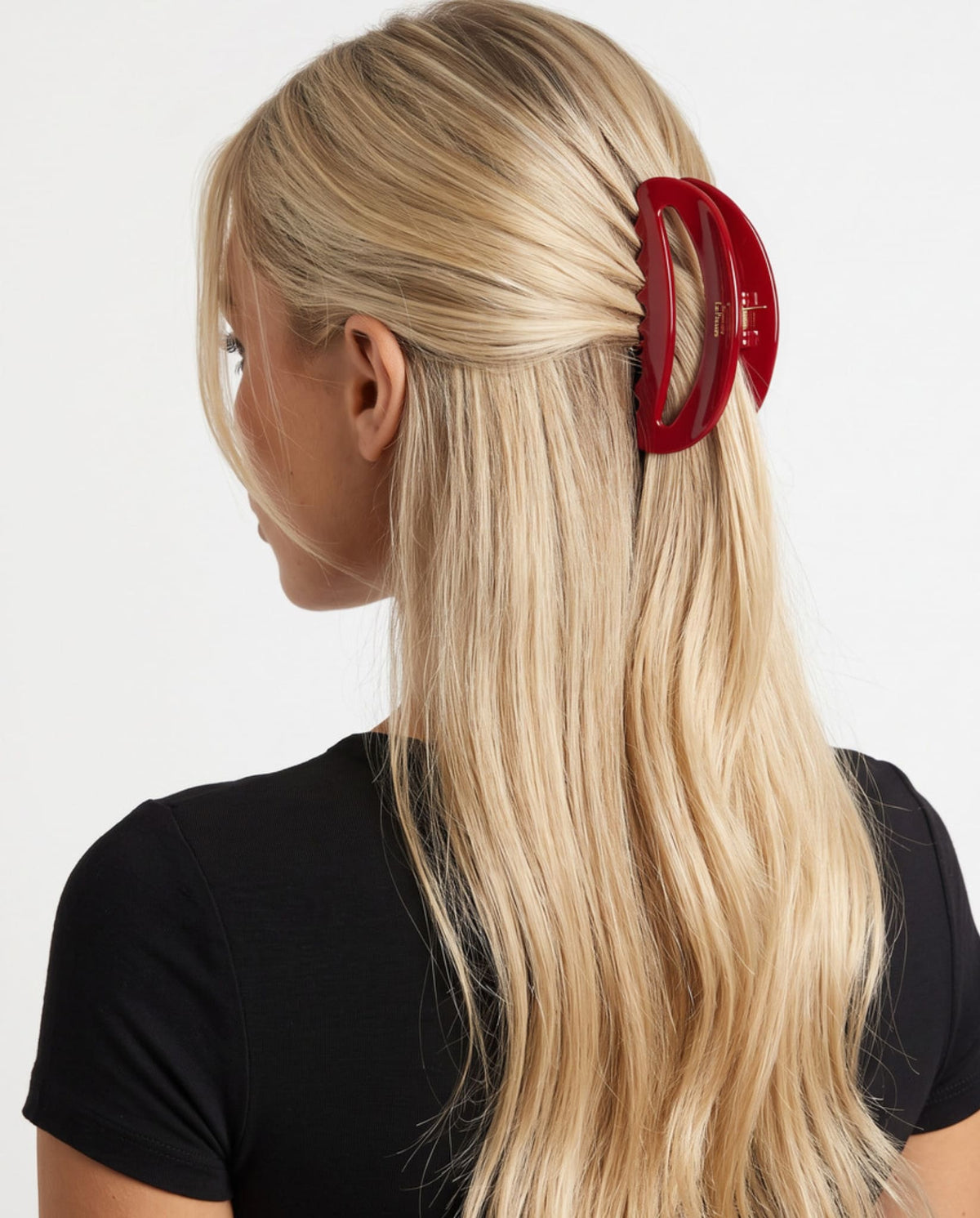 Large red hair claw clip securing blonde hair in a half-up hairstyle, shown from the side.