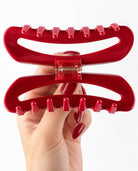 Close-up of the red hair claw clip opened to reveal its interlocking teeth and gold-tone spring mechanism.