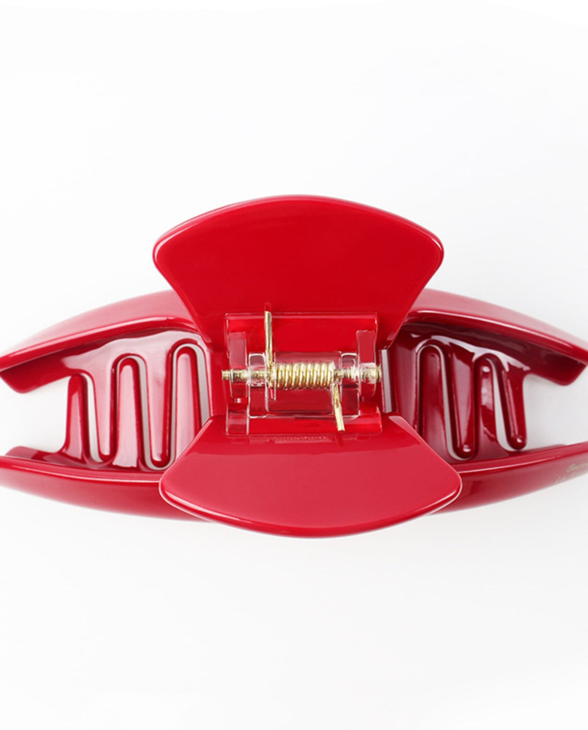 Close-up of an open red hair claw clip showing its curved teeth and metal spring mechanism.
