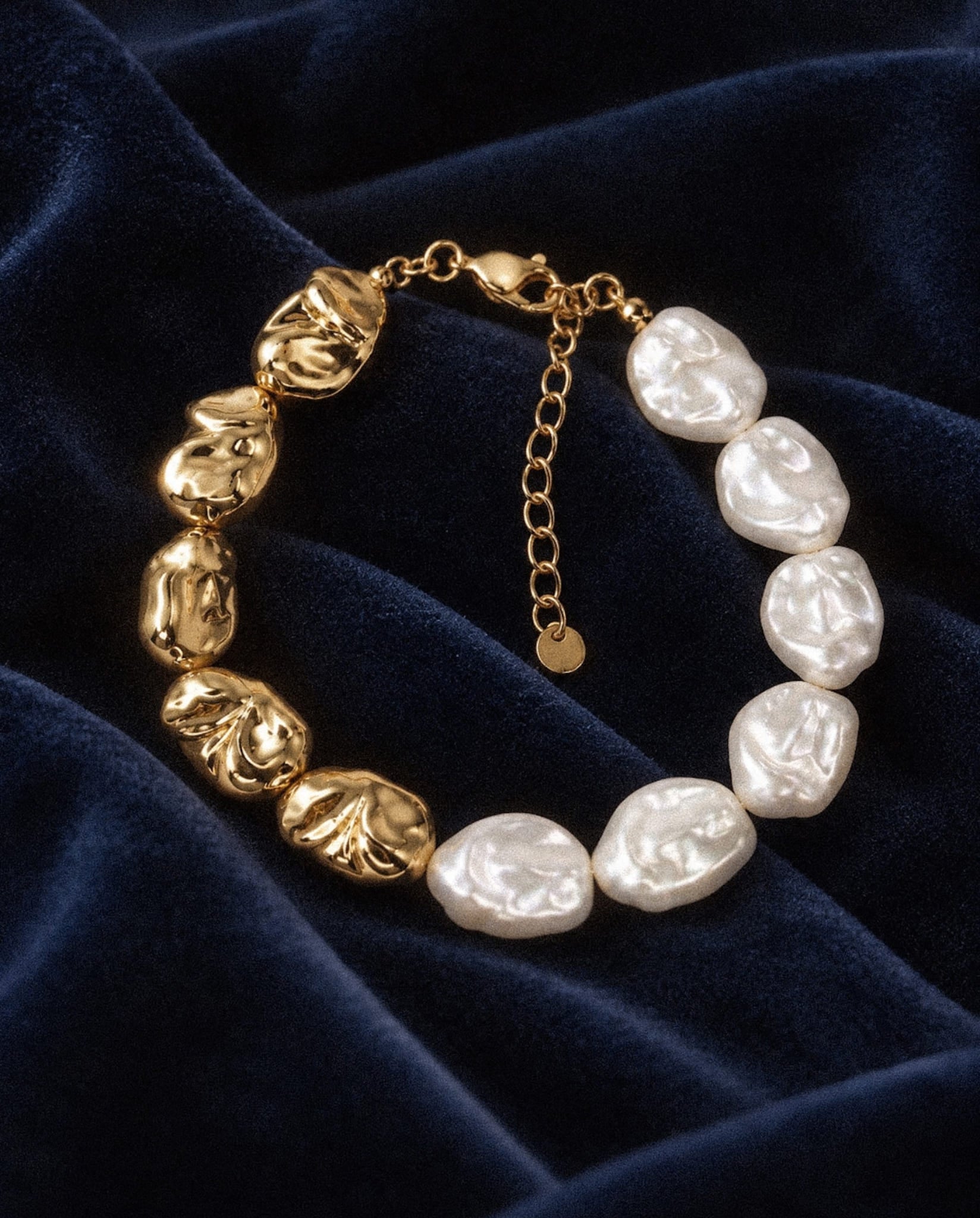 Sculpted Pearl Bracelet with irregular white pearl beads and textured gold-tone beads on navy velvet.
