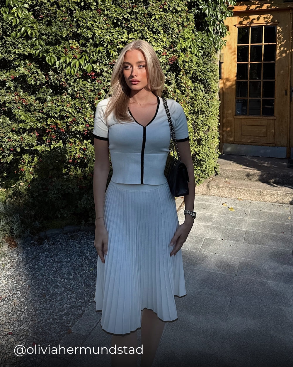 Olivia wearing a white pleated skirt set from Coventina Collection
