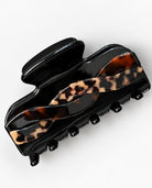 Glossy black hair claw clip with an intertwined tortoiseshell pattern in brown and beige, shown at an angle on a white background.