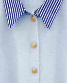 Detailed view of the striped collar and gold buttons on the blue cardigan.