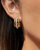 Gold triple hoop earrings with pearl detail worn on ear